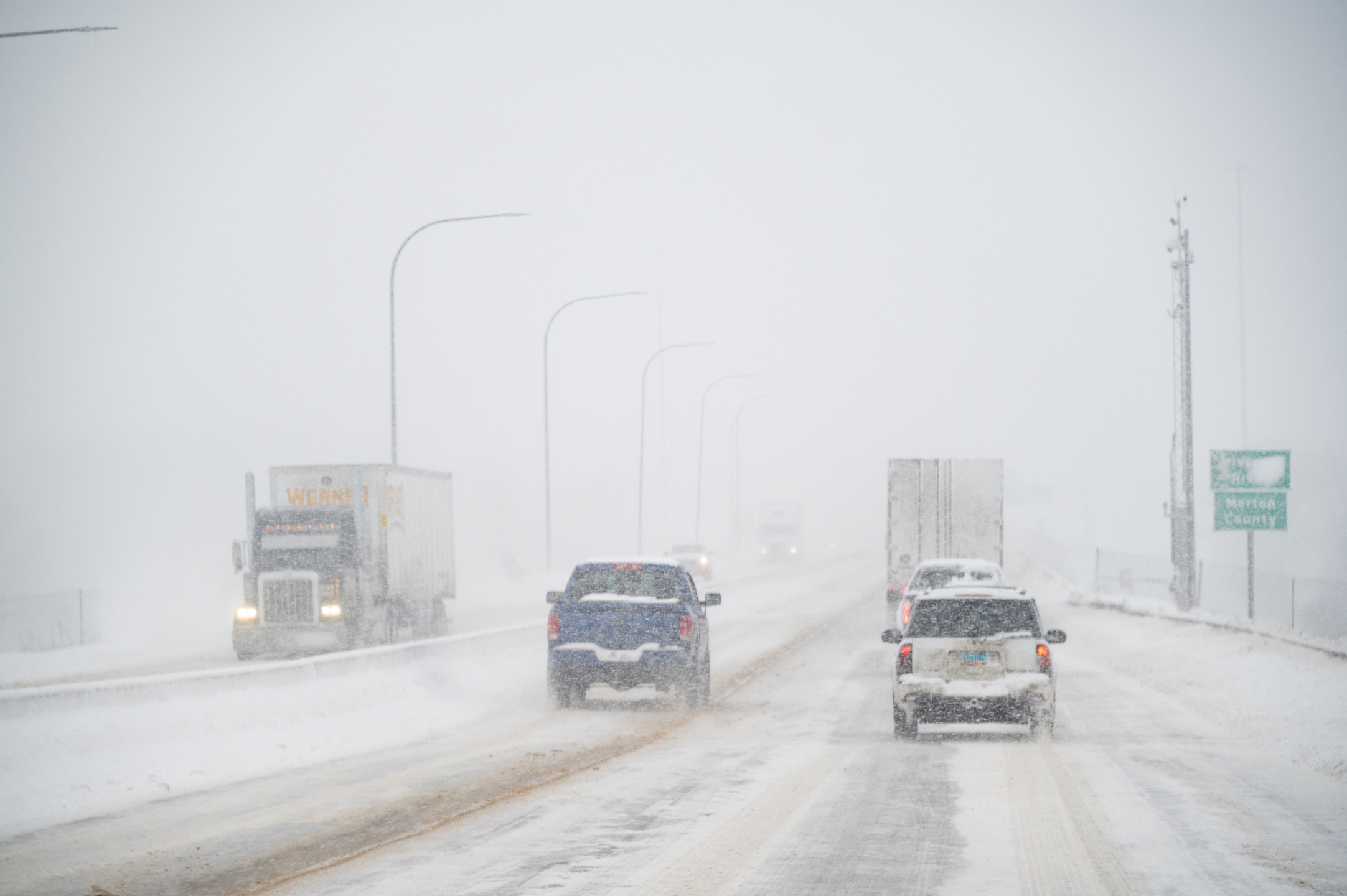 Cars and trucks driving on a snowy highway.