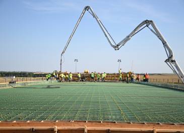 A view of reinforced concrete being installed with a crane in the distance. 