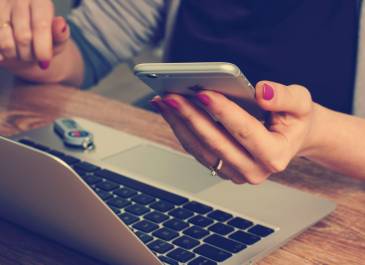 Up close woman using laptop and mobile phone.