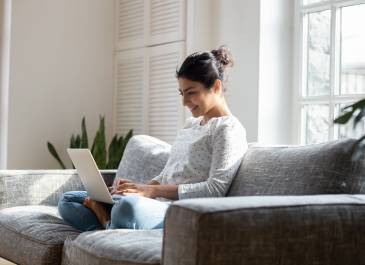 Resident seated on a couch using laptop.