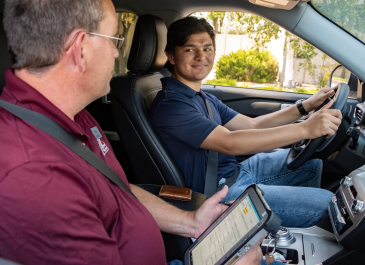Teen driver seated with an NDDOT employee taking his driver license test.