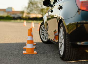 Driving school car next to traffic cones running a course.