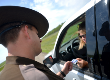 Highway patrol officer looking at a driver license.