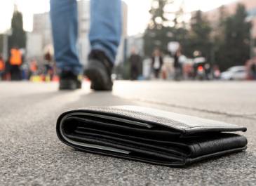 Wallet lays on a street while the owner walks away unknowingly.