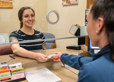 Young woman receives her new North Dakota driver license from smiling NDDOT employee.