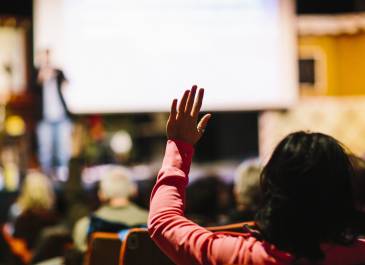 a person raises their hand at a public presentation