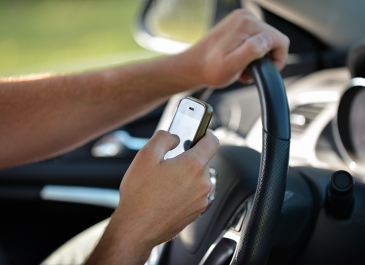 Hands using cell phone while driving.