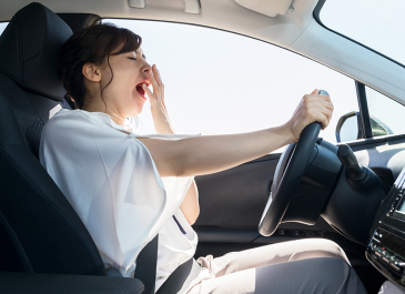 Young woman yawning while driving.