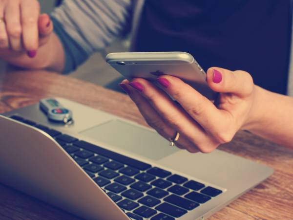 Up close woman using laptop and mobile phone.