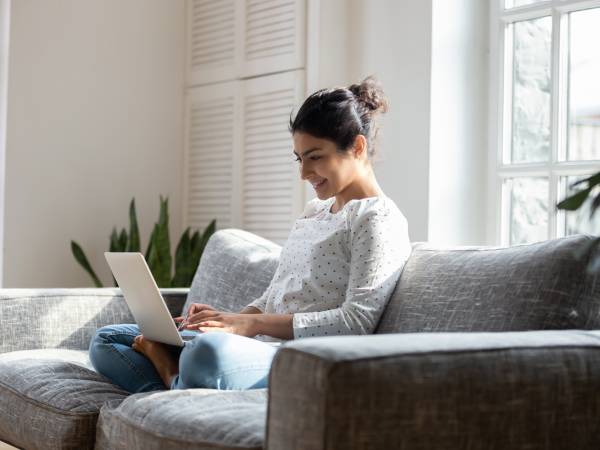 Resident seated on a couch using laptop.