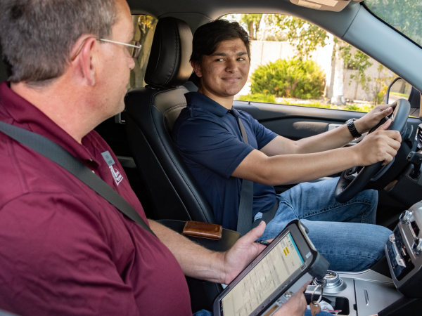Teen driver seated with an NDDOT employee taking his driver license test.