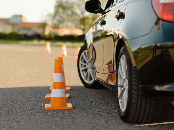Driving school car next to traffic cones running a course.