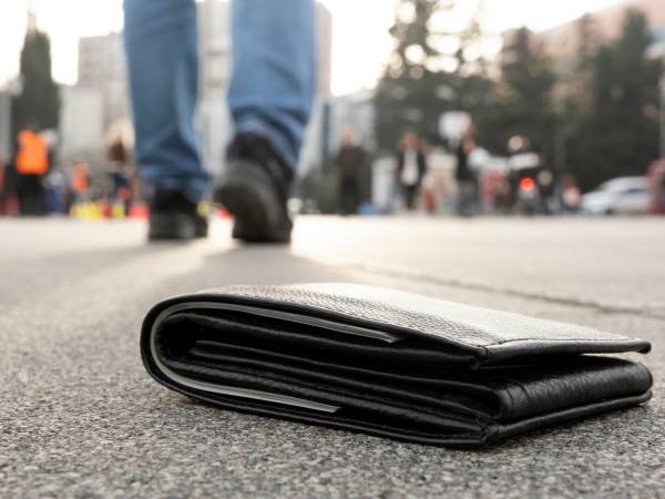 Wallet lays on a street while the owner walks away unknowingly.