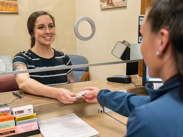 Young woman receives her new North Dakota driver license from smiling NDDOT employee.