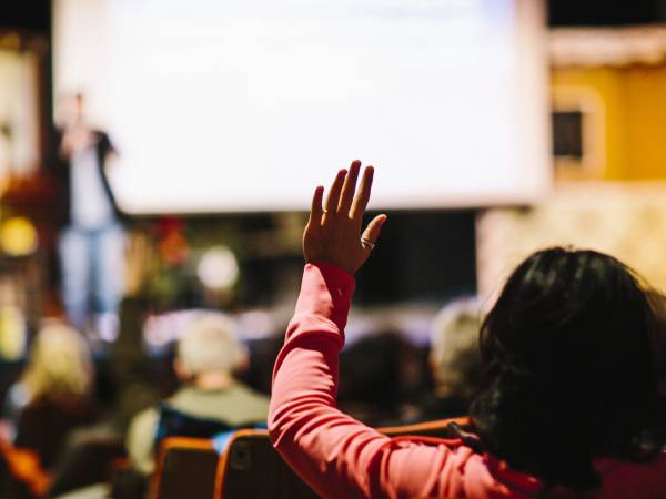 a person raises their hand at a public presentation