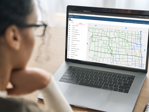 Woman looking at ND Roads, the North Dakota travel map, on her laptop computer.