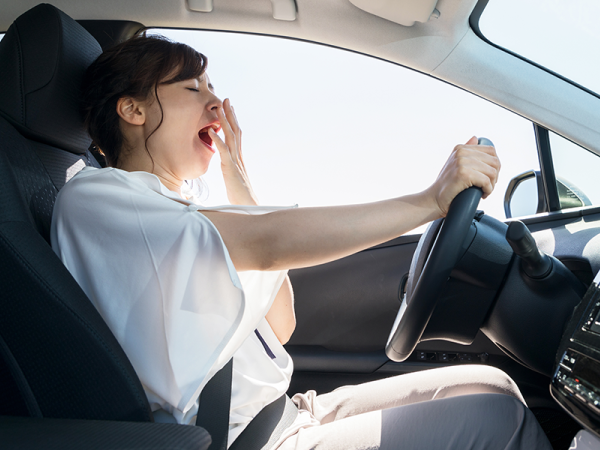 Young woman yawning while driving.