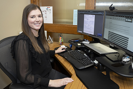 Brie Nyberg sits at her desk posing for photo. 