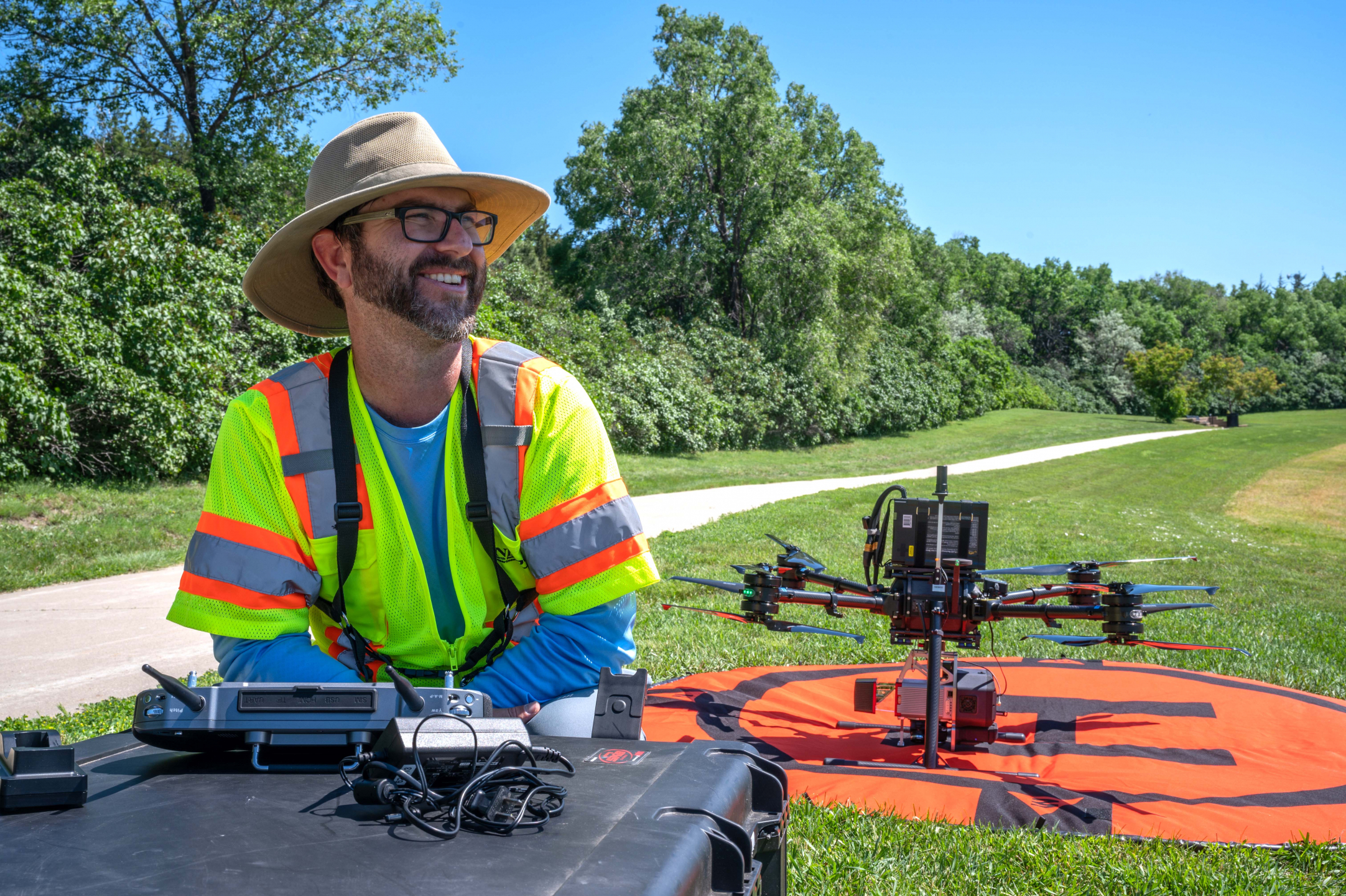 An NDDOT employee sits proudly next to the drone, ready to survey the area.