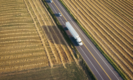 Aerial view of interstate hugged by field of crops on either side.