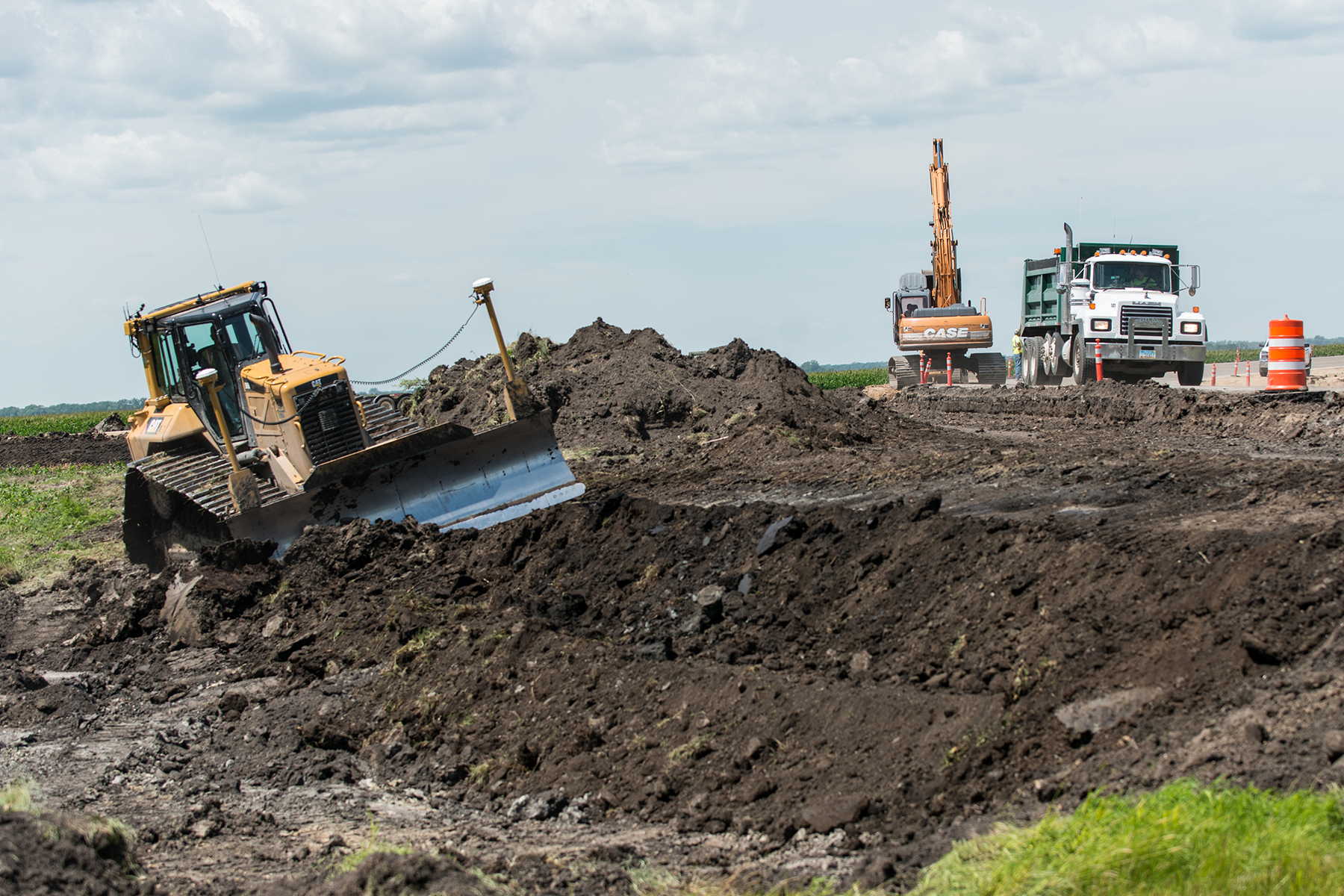 Bulldozer moves dirt with construction vehicles in the background.