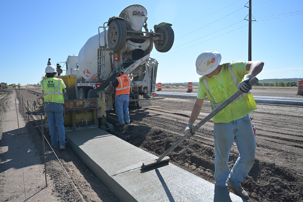 Construction contractors smoothing out cement on a works site.