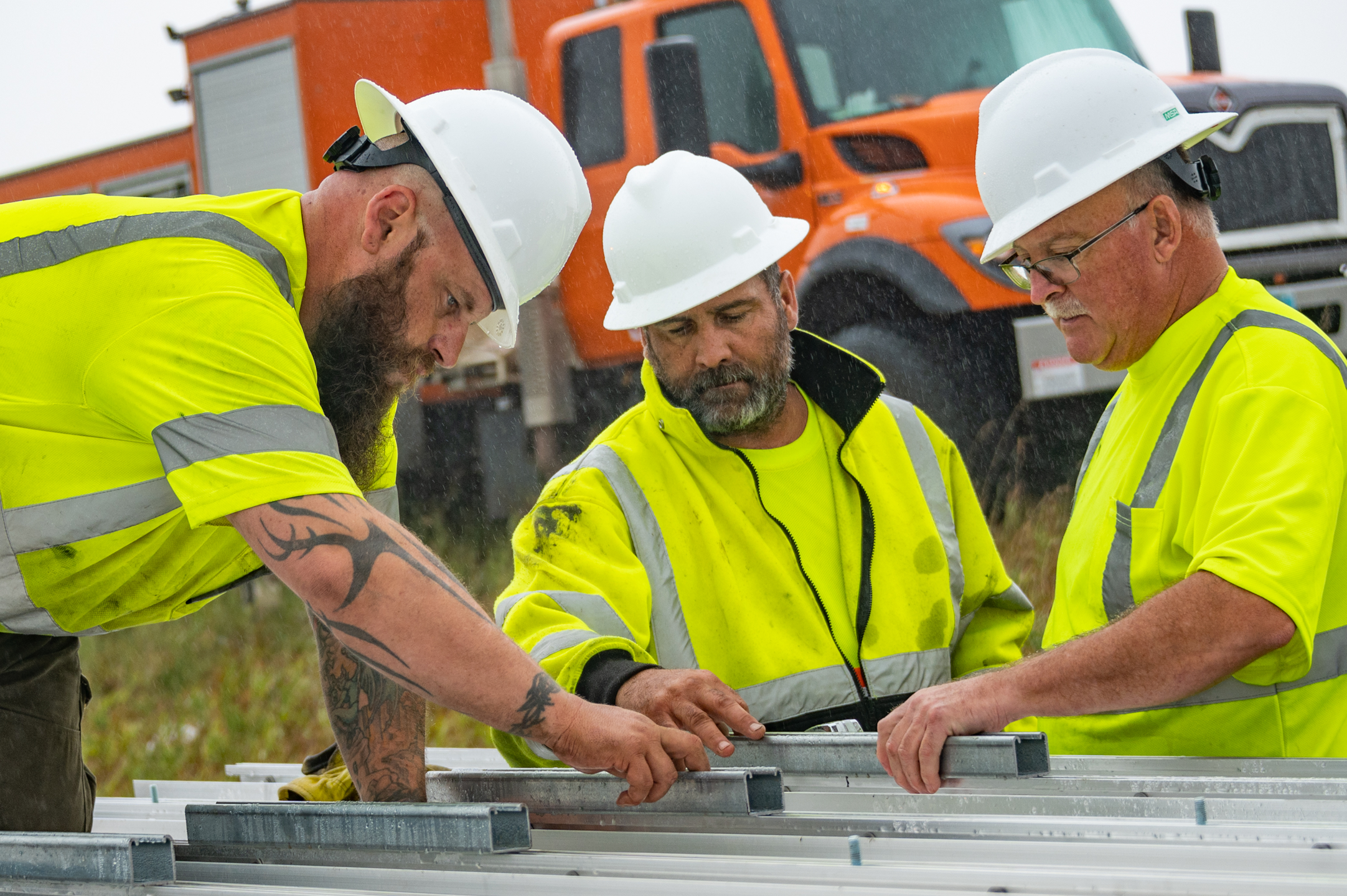 A group of construction workers in safety apparel collaborate.