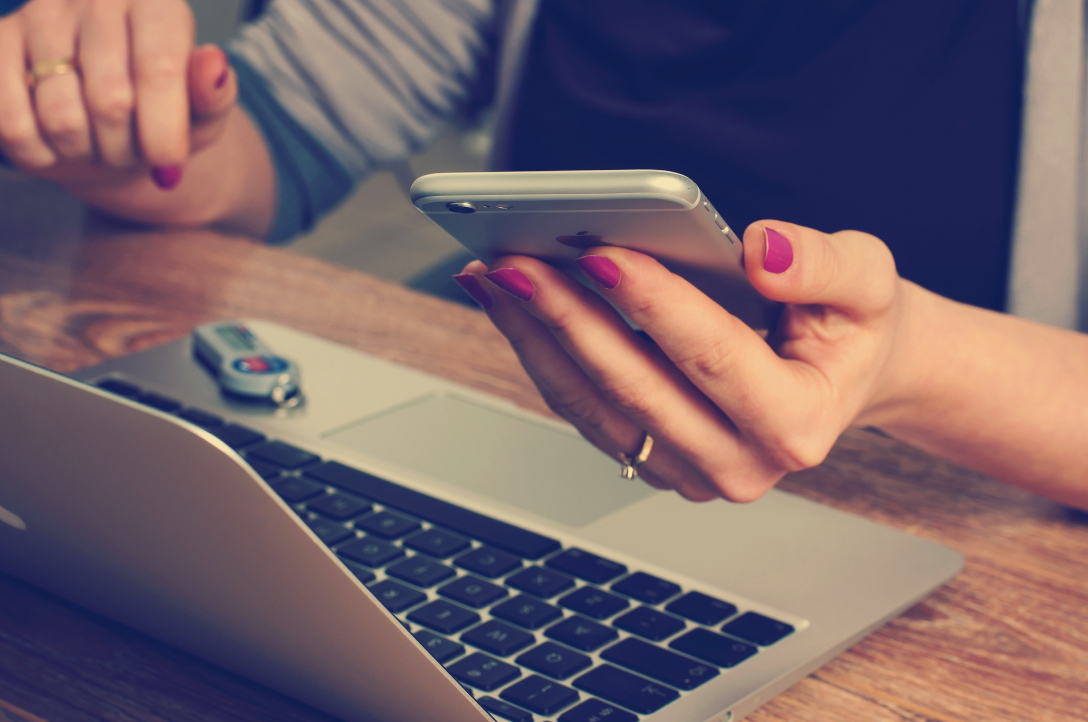 Resident  seated at wooden table in front of laptop, using a mobile phone.