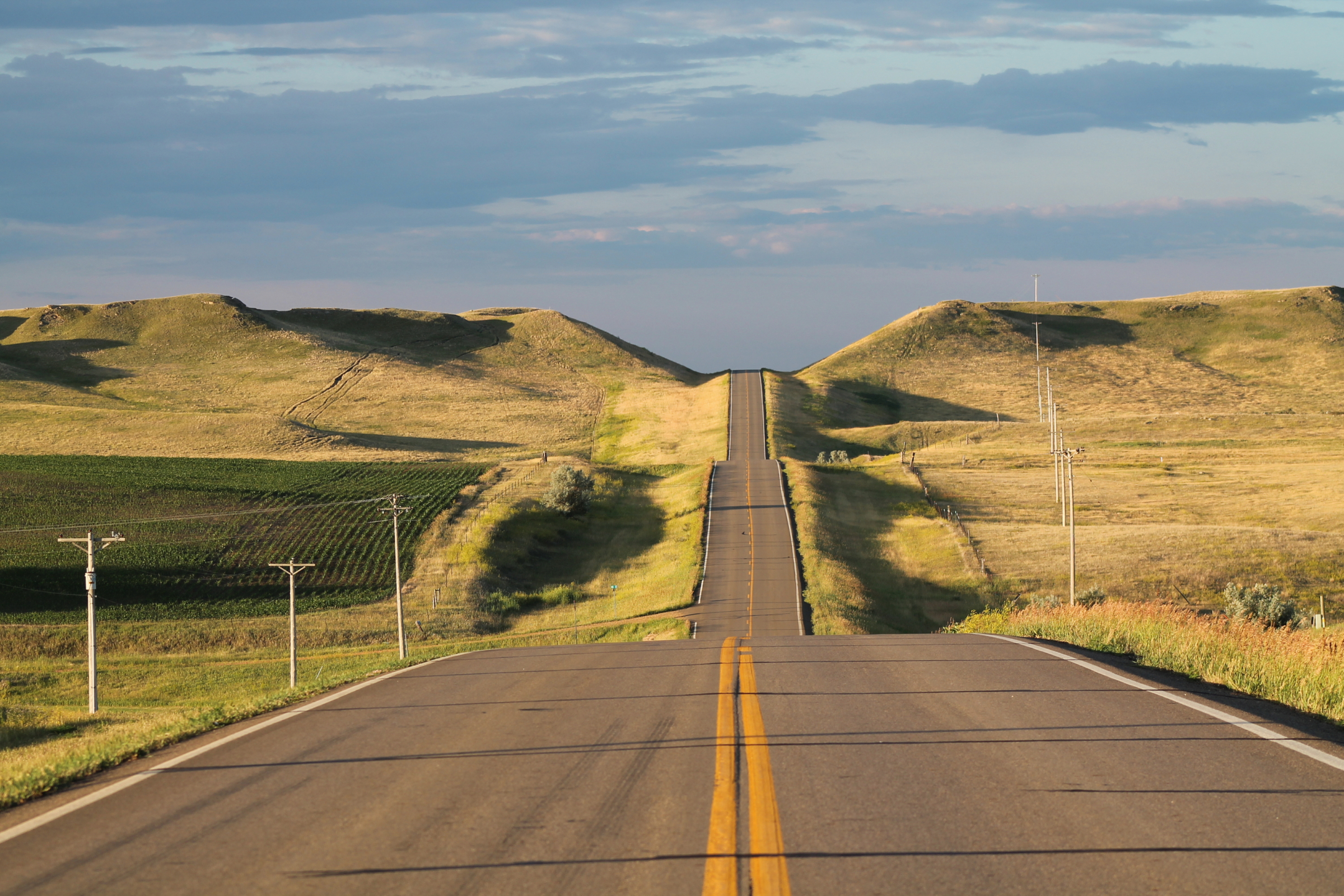 Empty rural road, paved, with farmlands on either sides