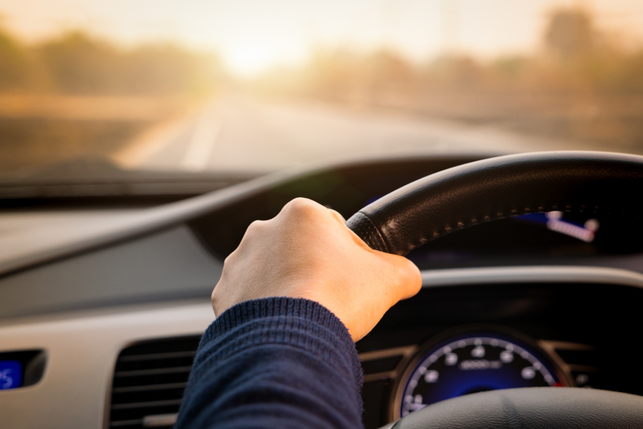 close up of hands on a steering wheel looking out the front windshield of car