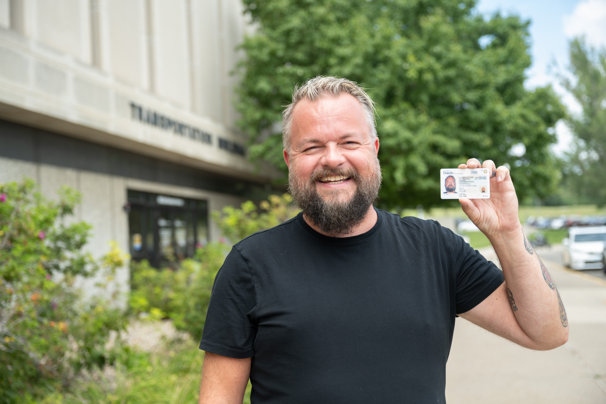 Man holding his new North Dakota driver license and identification card.