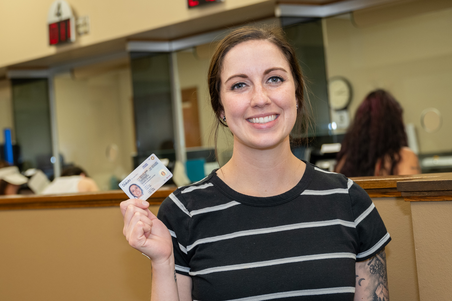 Young woman at the NDDOT holding her new driver license.