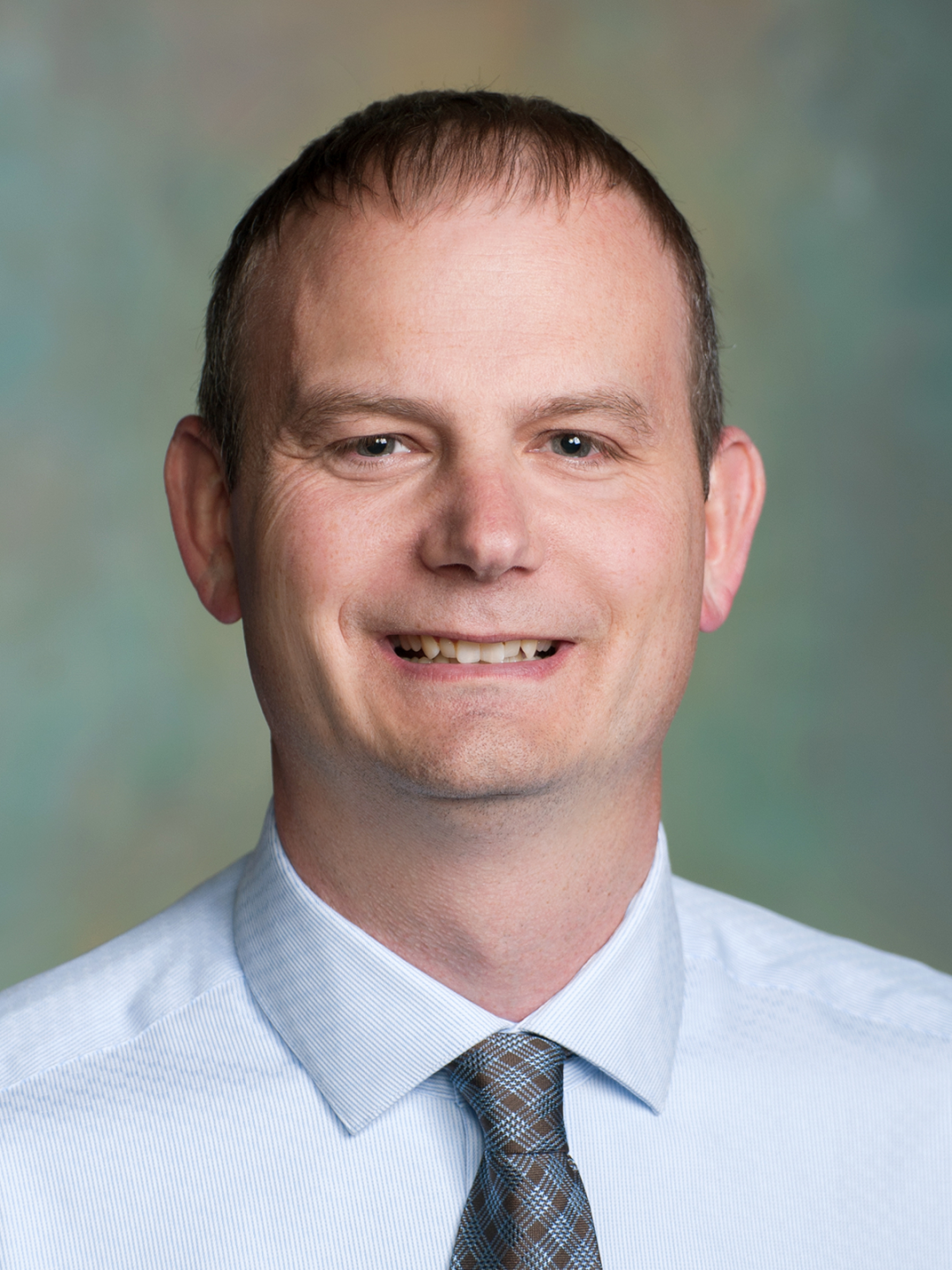 Smiling Chad M. Orn, PE, Deputy Director for Planning in front of multi-colored background.