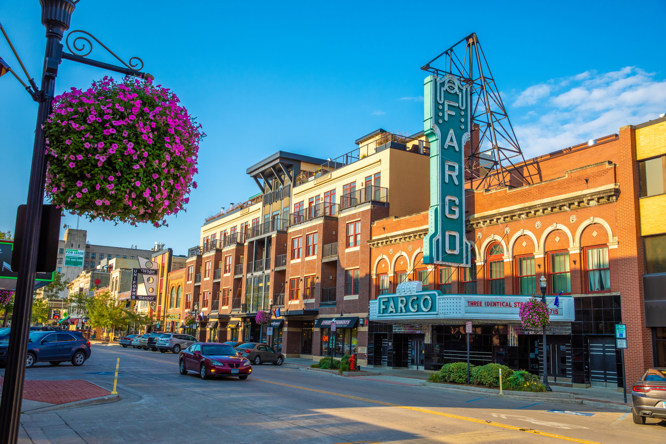 Downtown Fargo on a sunny day with the theatre in view and pink flowers in the foreground