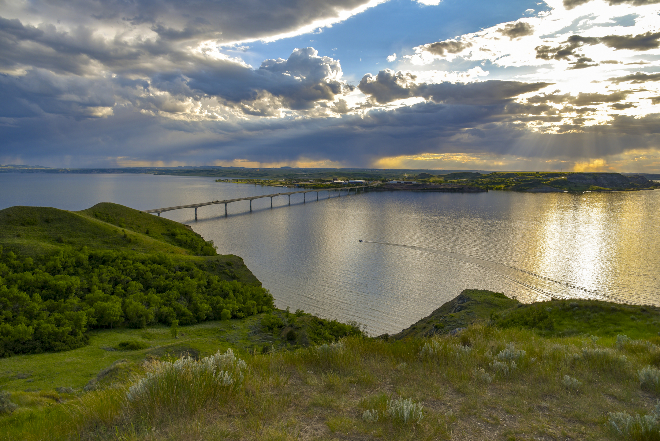 Sun shining down through the clouds over bridge over river