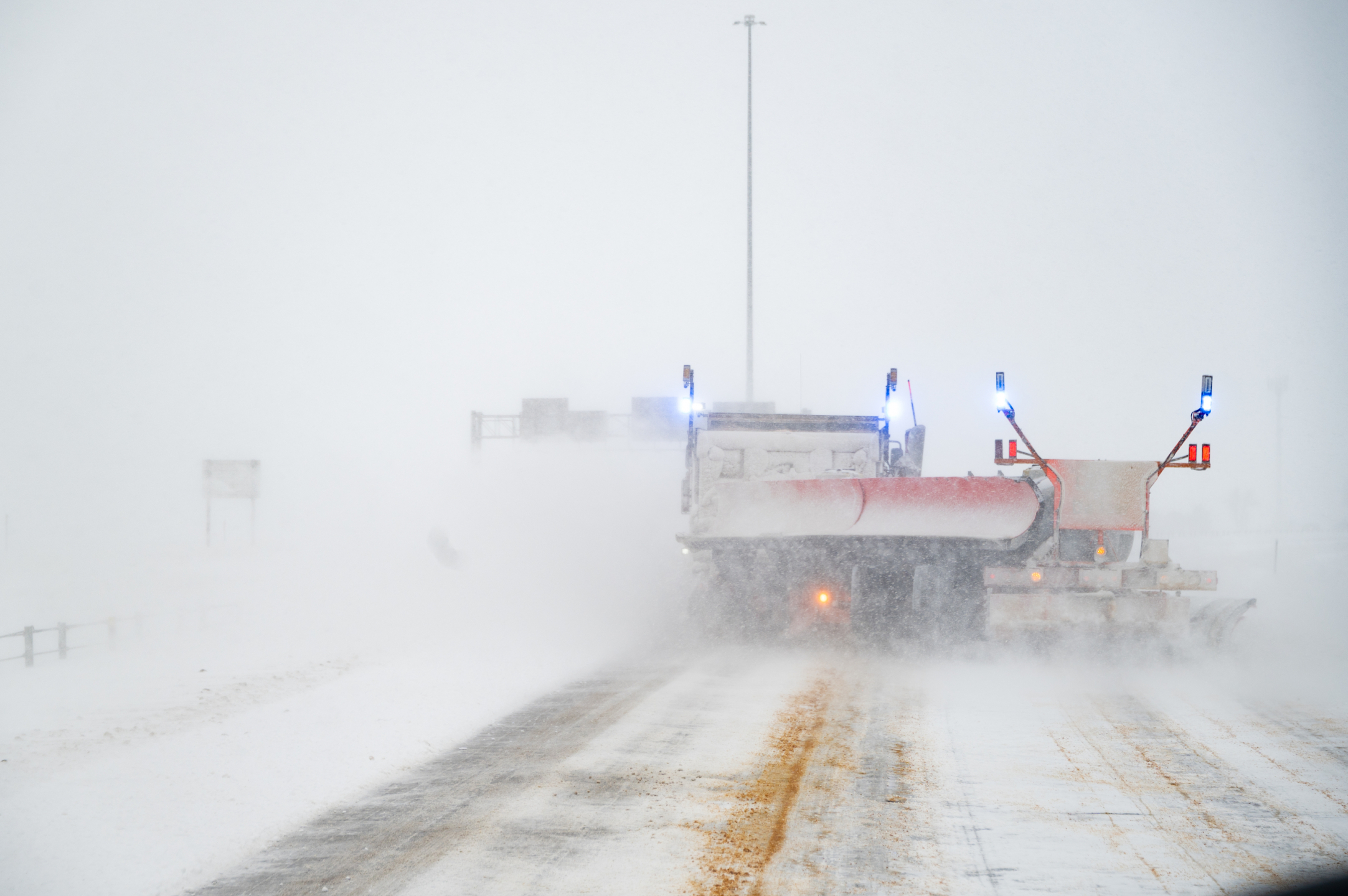 Photo of a tow plow on a snow-covered roadway. 