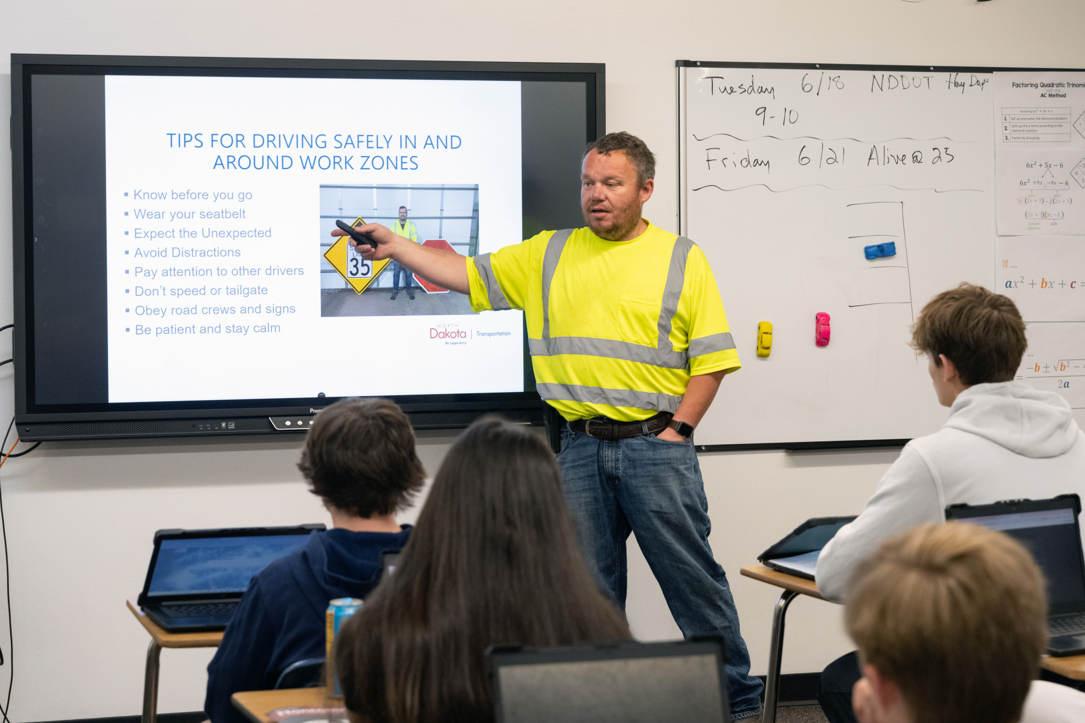 Wade Szudera stands in front of a classroom of teenagers as he points to a slide with work zone safety tips.