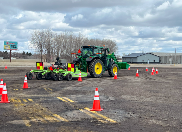 A tractor pulling a mower navigates an obstacle course