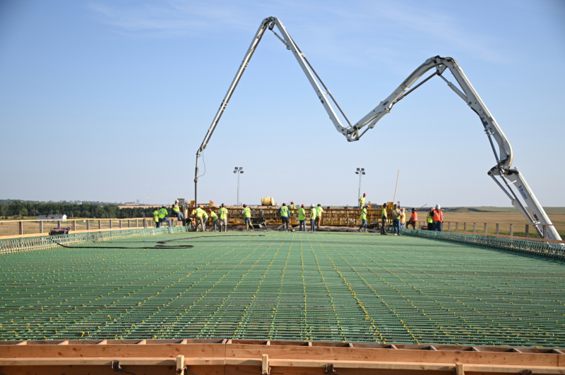 A view of reinforced concrete being installed with a crane in the distance. 