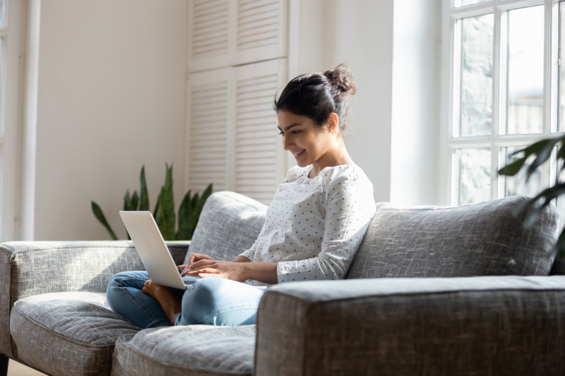 Resident seated on a couch using laptop.