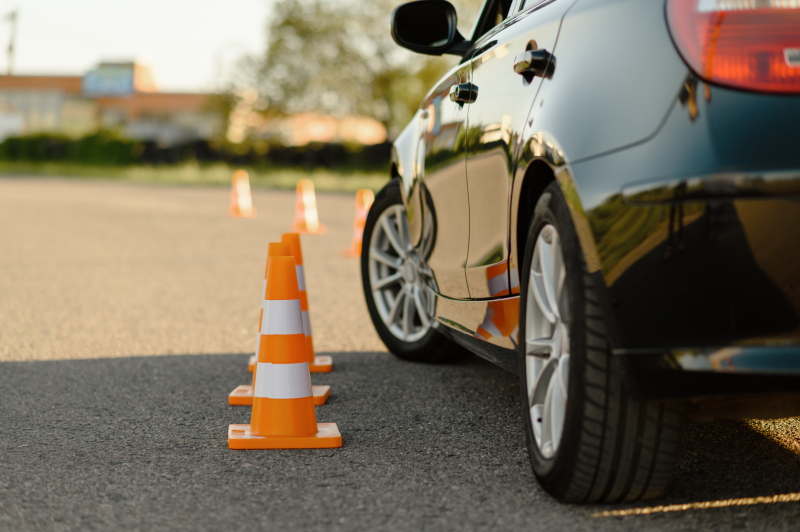 Driving school car next to traffic cones running a course.