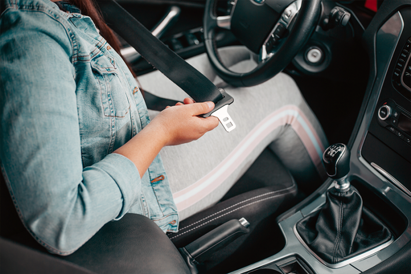 Woman putting on seat belt.