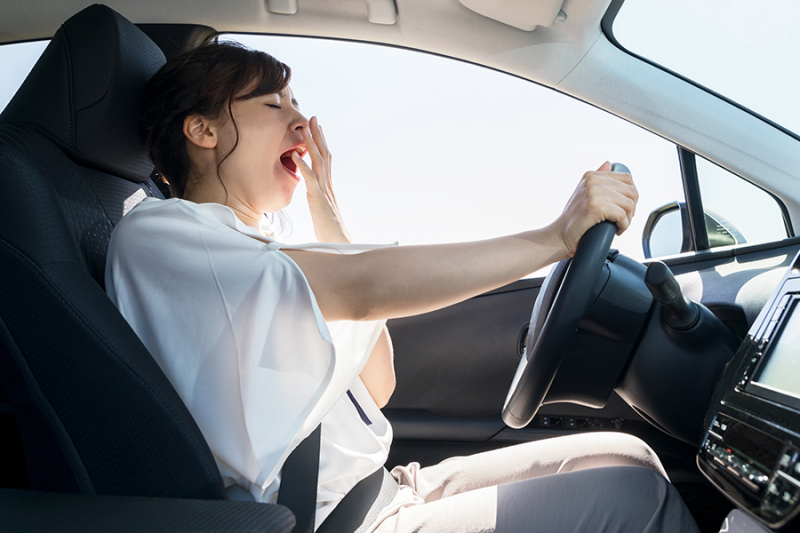 Young woman yawning while driving.